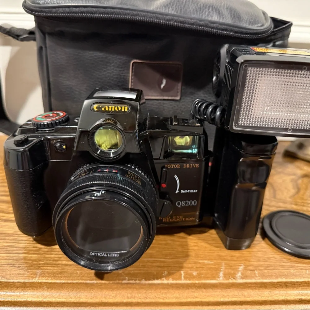 Vintage Canon camera with a flash attachment and carrying case.